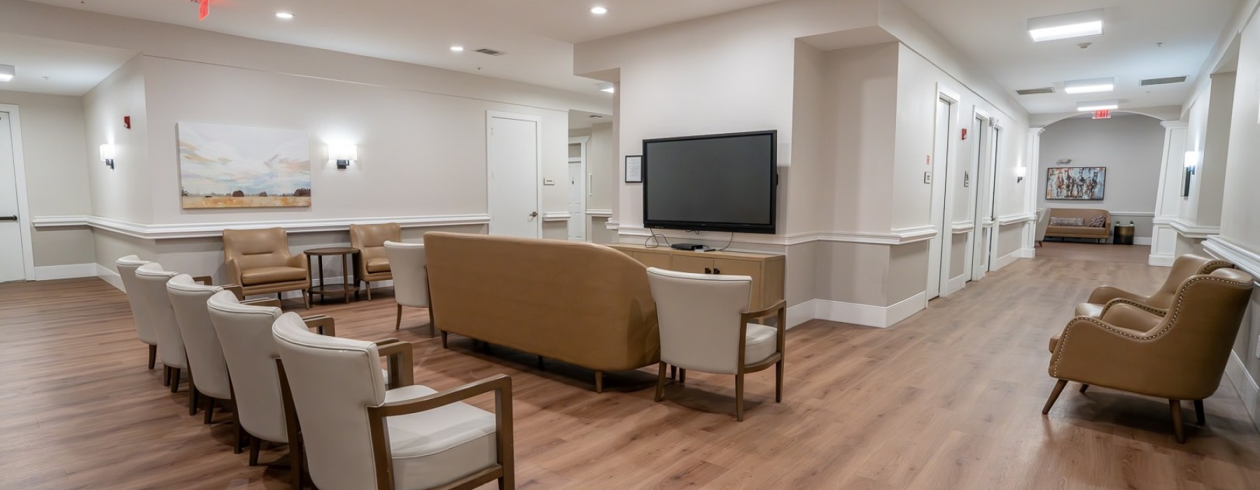 a room with  a row of chairs and a couch facing a wall with a tv